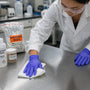 Researcher decontaminating Phenibut residue from a stainless steel lab bench