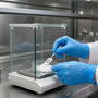 Gloved hands weighing aniracetam powder in a laboratory fume hood